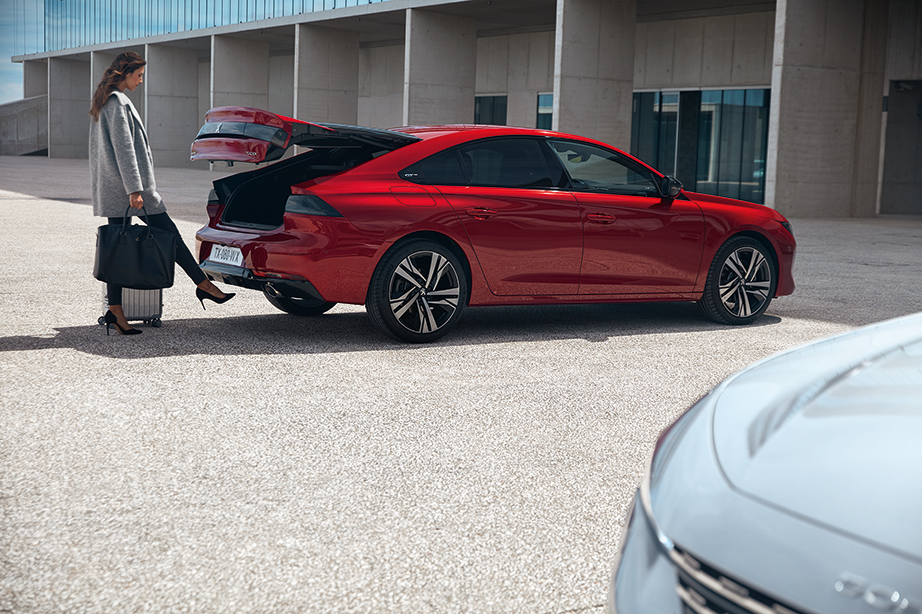 Peugeot 508 vid en parkering med en kvinna som öppnar bakluckan.
