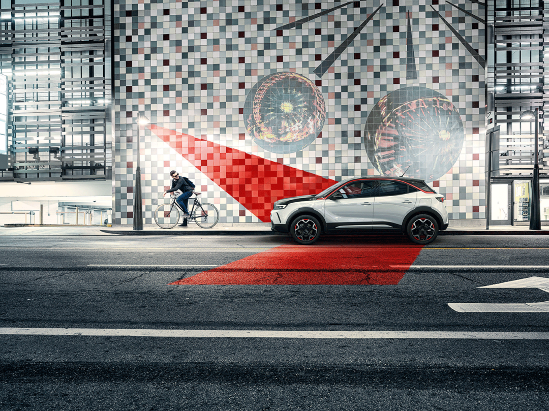 Opel Mokka, parkerad vid trottoar och en cyklist cyklar förbi